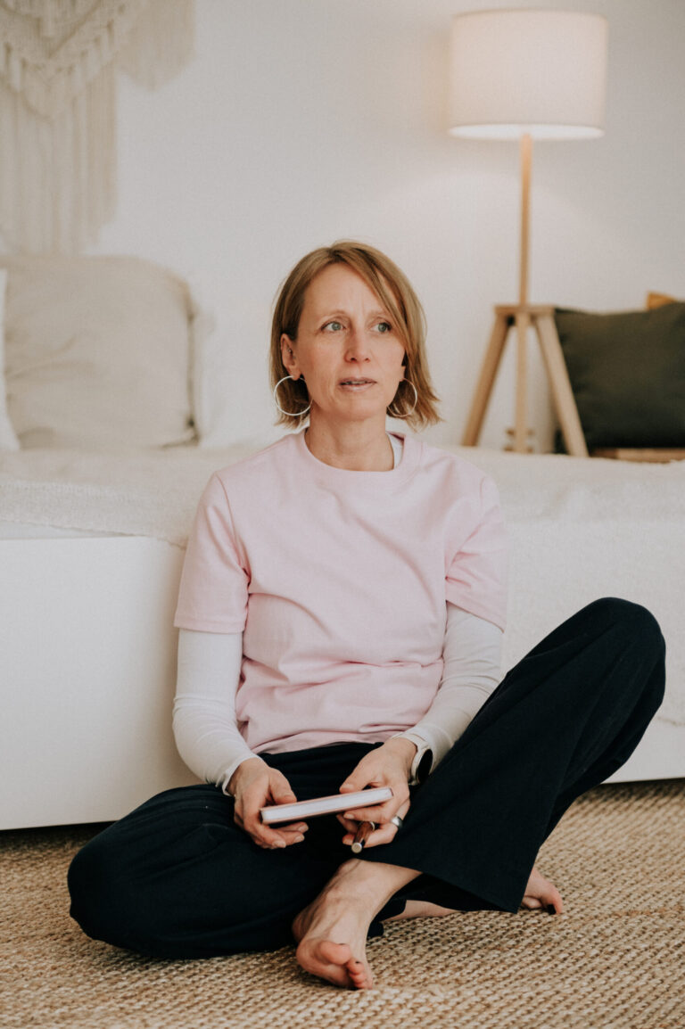 Stefanie Warnken auf dem Boden sitzend, vor einem Bett